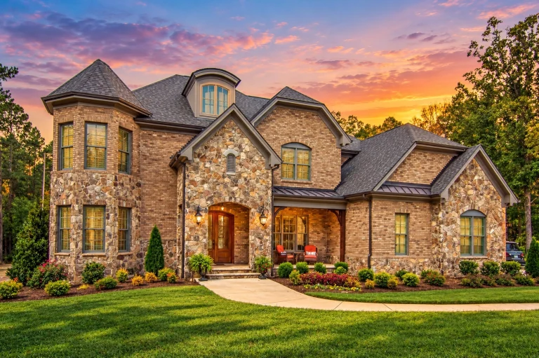 Front elevation of a New American style luxury home featuring brick and stone exterior, steep gabled rooflines, arched entry, and balanced modern traditional architecture