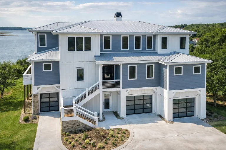 Front exterior view of a luxury coastal style home with elevated foundation, horizontal siding, multiple garages, and expansive balconies overlooking the water