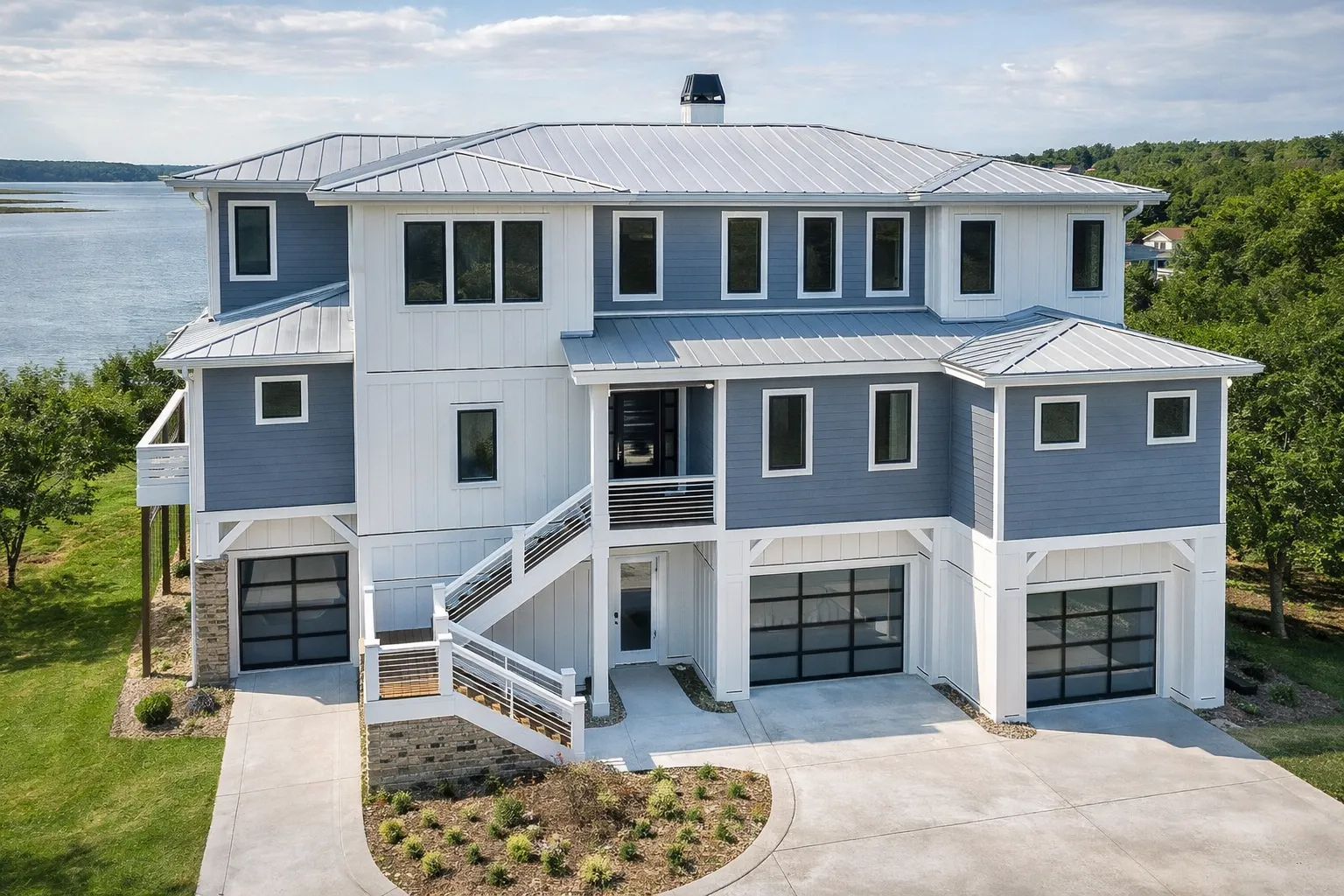 Front exterior view of a luxury coastal style home with elevated foundation, horizontal siding, multiple garages, and expansive balconies overlooking the water