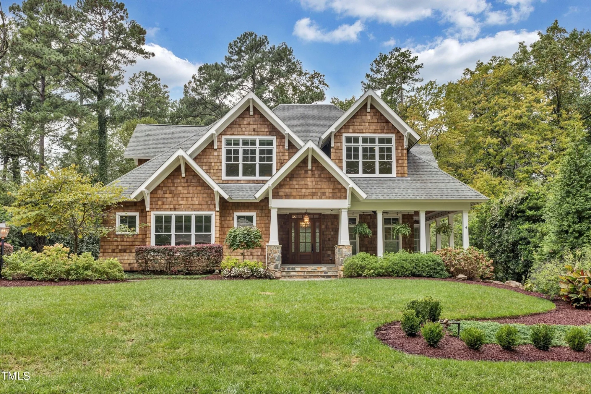Front elevation of a Traditional New American brick house with symmetrical gables, dark trim windows, and classic covered entry
