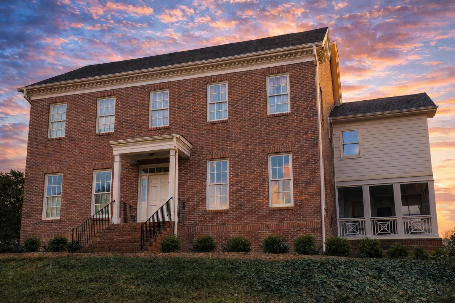 Front elevation of a Georgian Colonial style home with red brick exterior, symmetrical window placement, central entry door, and classic shutters