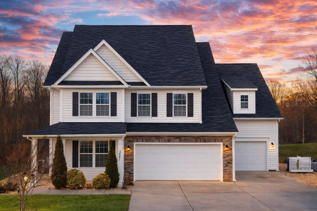 Front elevation of a Traditional Colonial style home with gray horizontal siding, white trim, symmetrical windows, and a double front-entry garage