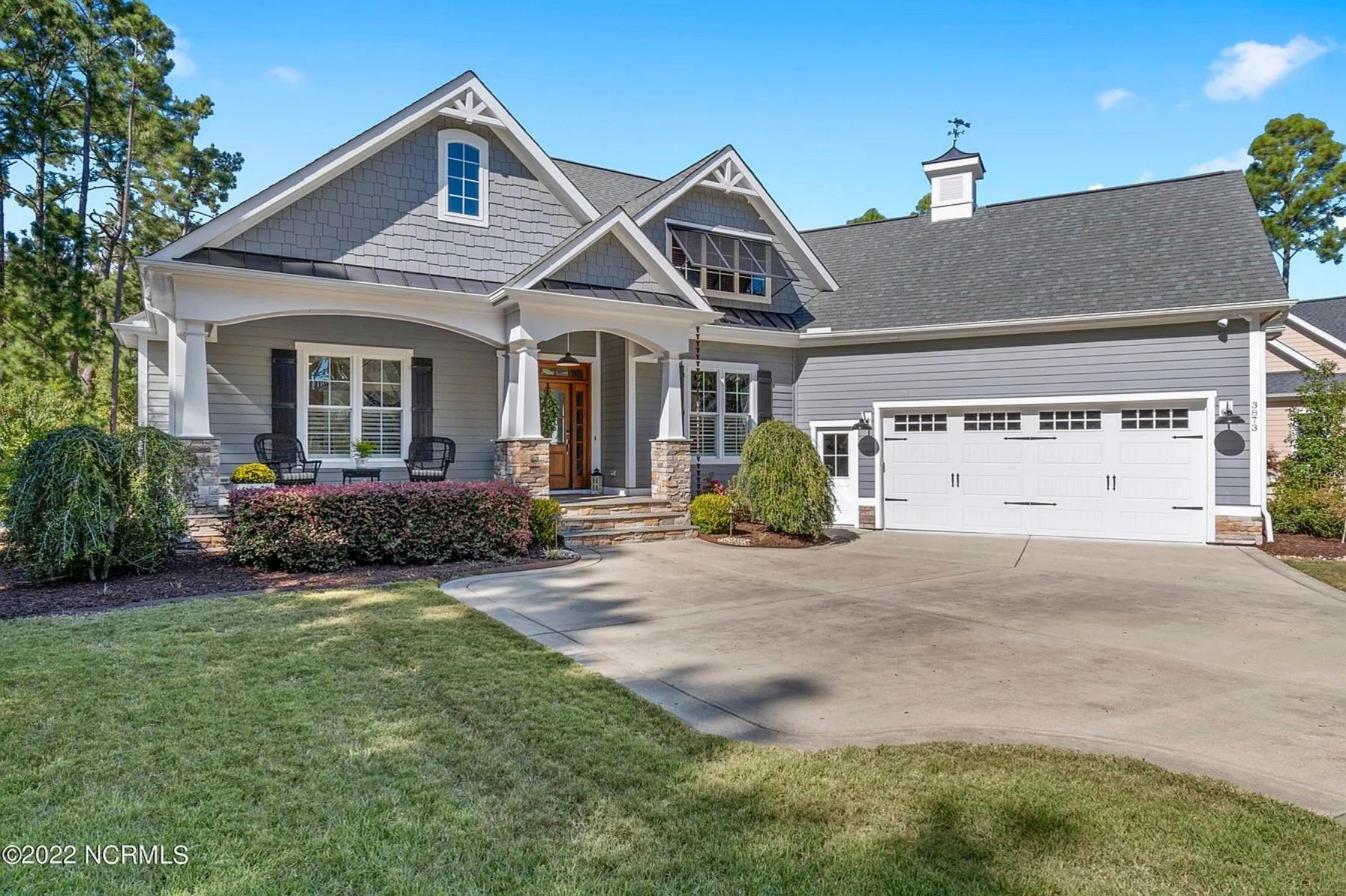 Front exterior of a New American Traditional Suburban style home with horizontal lap siding, board-and-batten accents, covered front porch, and side-entry garage