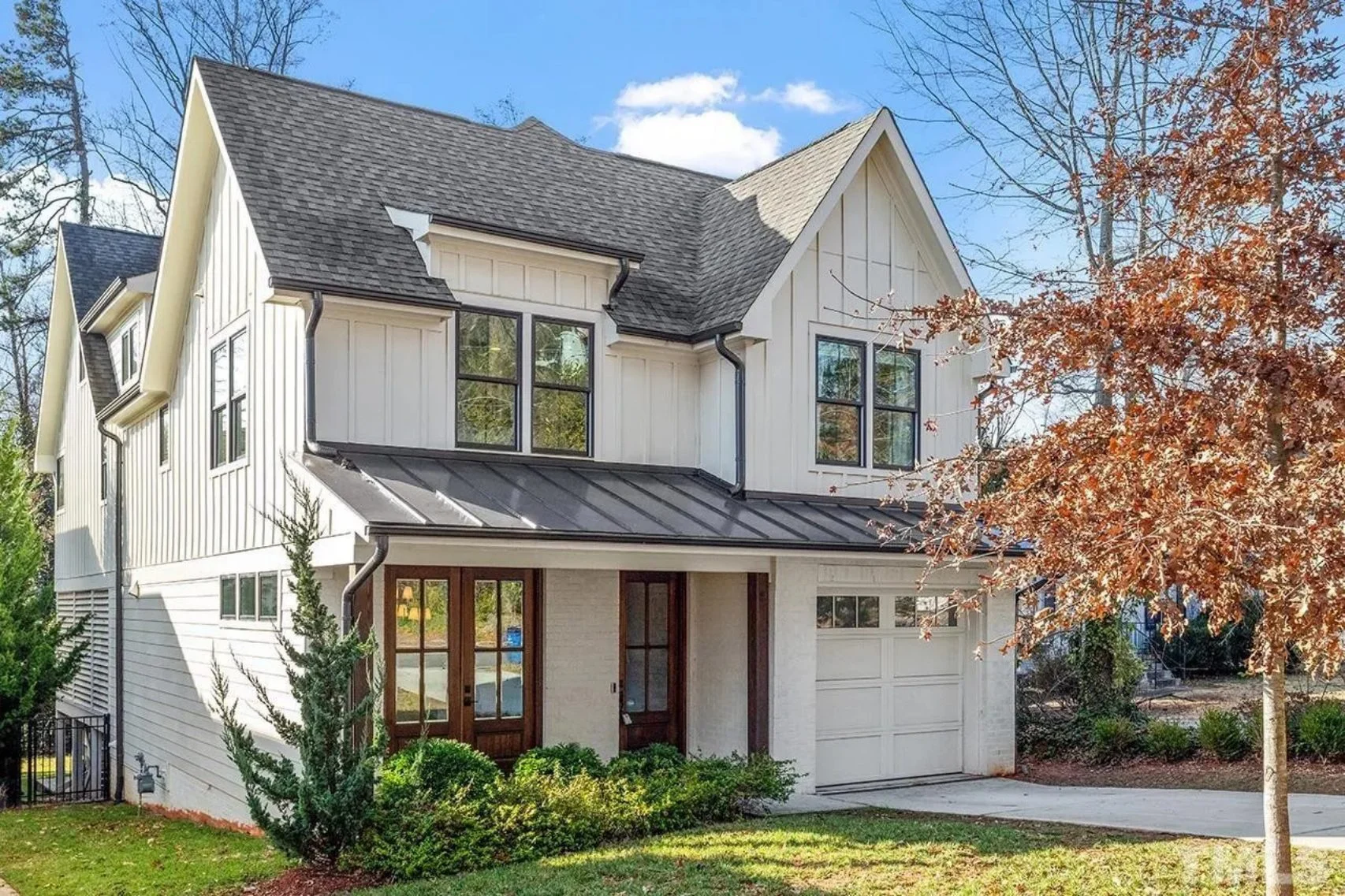Front exterior view of a Modern Farmhouse New American style home featuring board and batten siding, gabled rooflines, and a covered entry porch