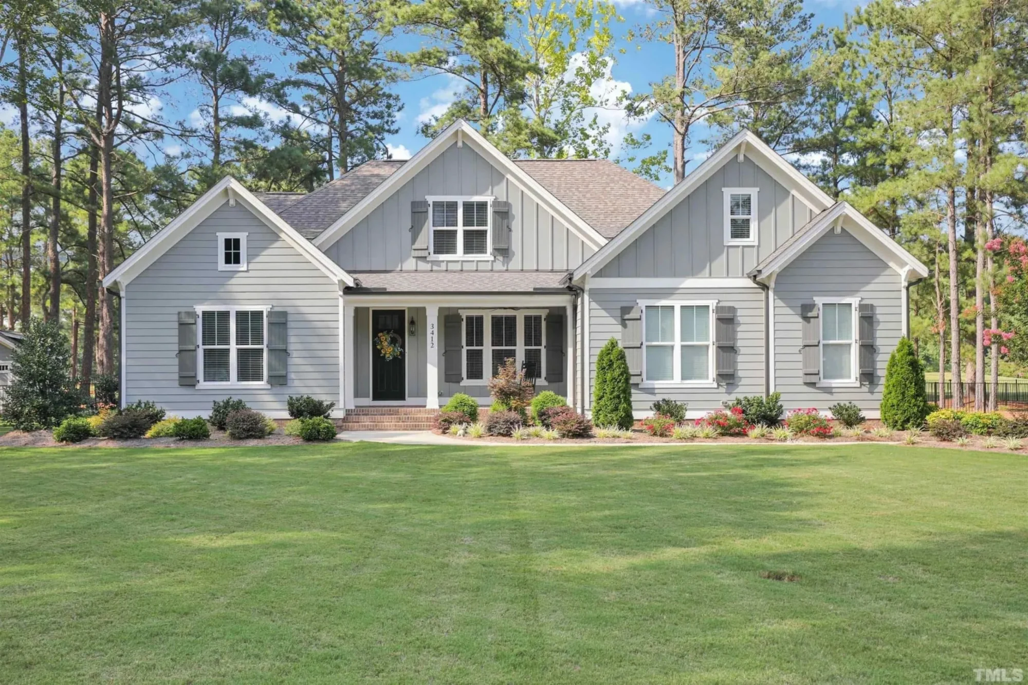 Front elevation of a New American Modern Farmhouse style home featuring board and batten siding, gabled rooflines, and expansive front lawn