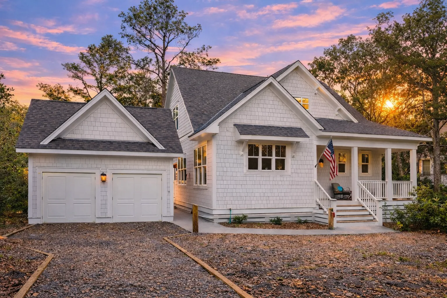 Front exterior of a coastal shingle style cottage home featuring cedar shake siding, detached garage, covered front porch, and classic Cape Cod detailing