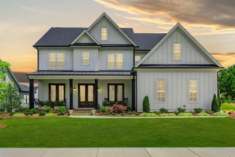 Front elevation of a modern farmhouse style home featuring board and batten siding, gabled rooflines, symmetrical windows, and a welcoming covered porch