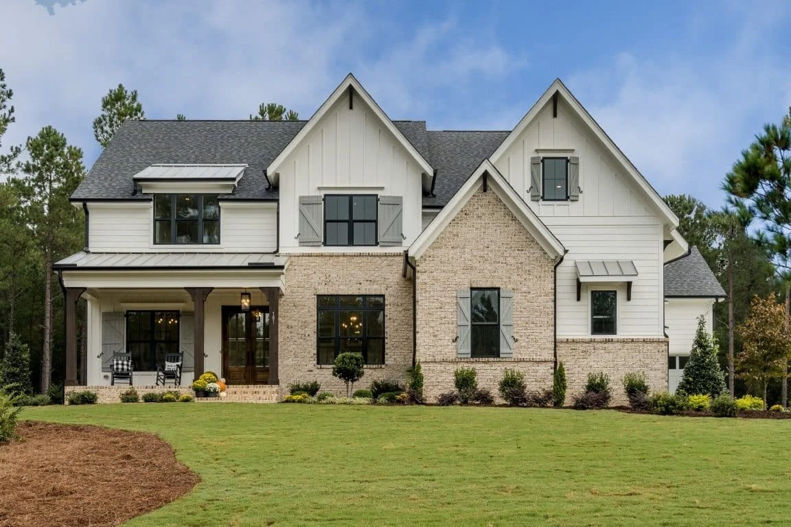Front exterior view of a New American Modern Traditional home featuring painted brick, board and batten siding, steep gables, and a covered front porch
