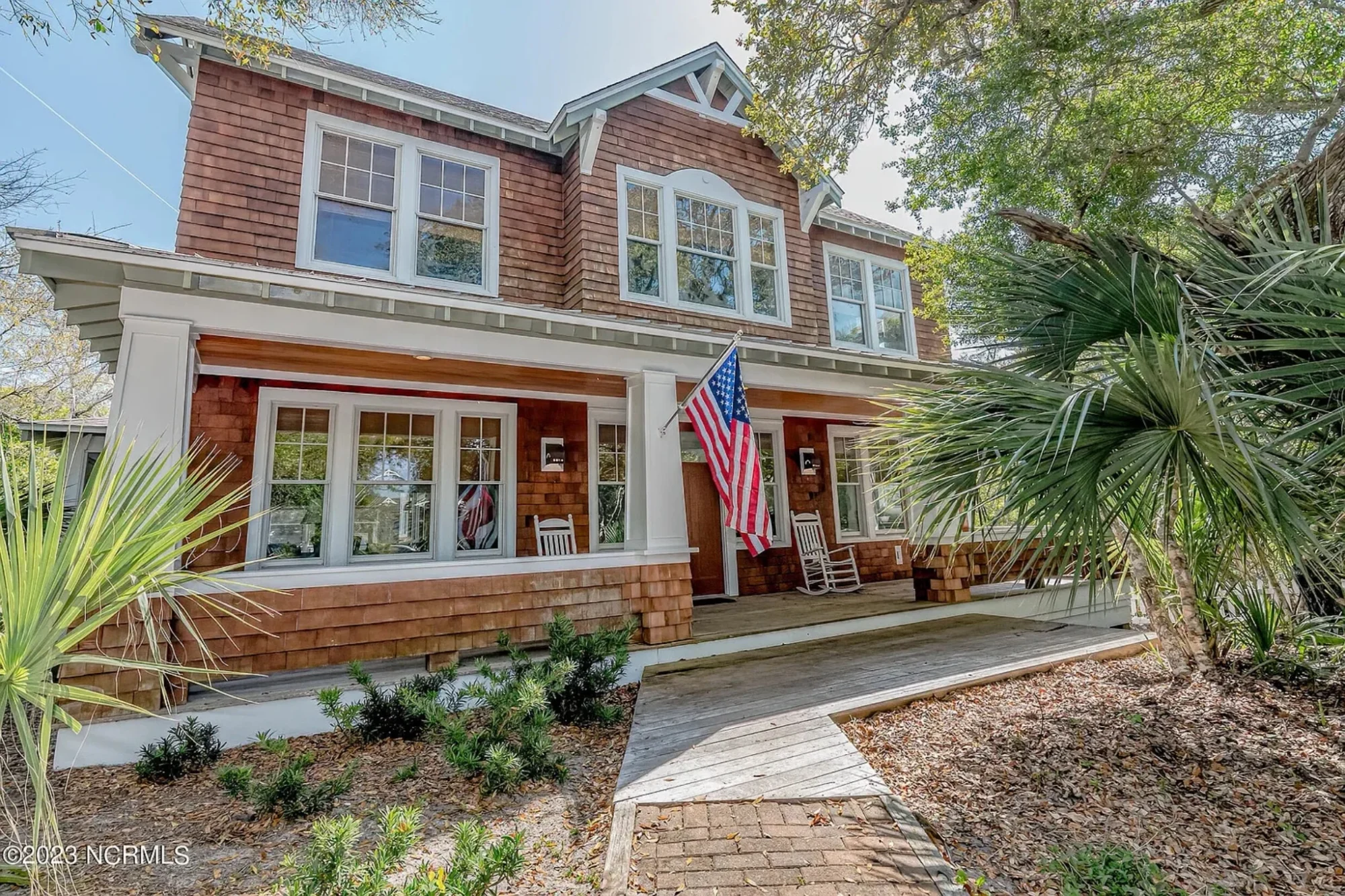 Front exterior of a Charleston style Southern home with brick façade, double stacked porches, white columns, and traditional colonial detailing