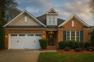 House Plans with Open Floor Plan 8 Traditional brick ranch-style home with Craftsman details, featuring a front gable roof, dormer window, and two-car garage with landscaped yard under warm afternoon light.